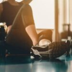 A woman taking a break after doing workout with a protein and dumbbell placed beside at gym. Inside out health and beauty.